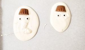 Candy eyes placed on the white chocolate snowmen.