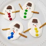 Four decorated melted snowman bark pieces on a white plate.