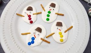Four decorated melted snowman bark pieces on a white plate.