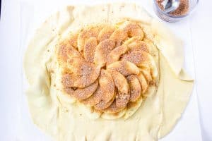 Pastry dough topped with sliced apples and cinnamon sugar.