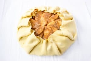 Unbaked apple galette with folded pastry edges.