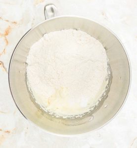 Flour added to the creamed mixture in the bowl.