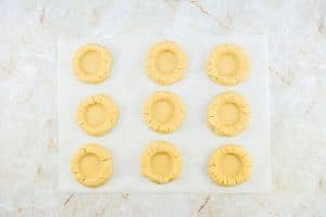 Cookie dough rounds shaped with indentations in the center.