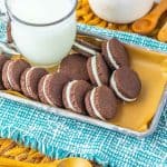Top-down view of a tray of homemade Oreos and a glass of milk.
