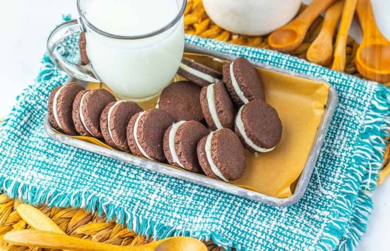 Top-down view of a tray of homemade Oreos and a glass of milk.