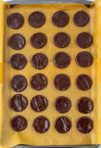 Chocolate cookie rounds arranged on a baking sheet.