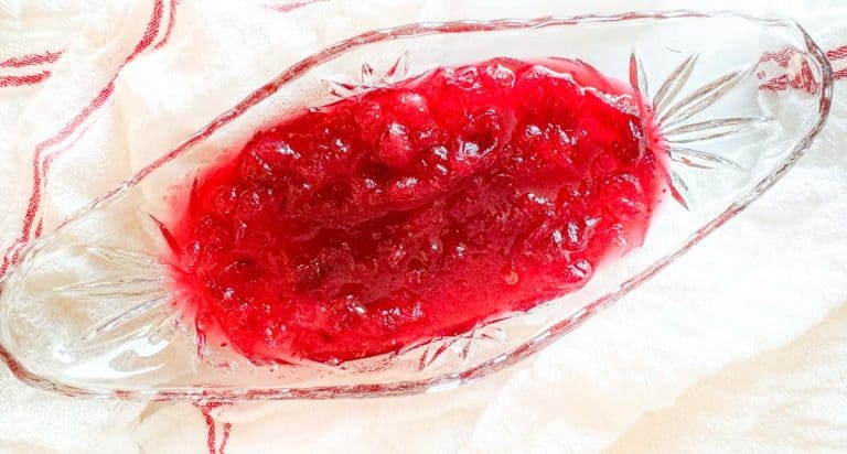 Overhead view of a glass serving dish filled with bright red cranberry sauce.
