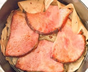 Close view of ham steaks with glaze and brown sugar in the air fryer basket.