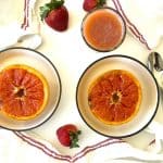 Broiled Grapefruit served in bowls with spoons and strawberries.