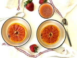 Broiled Grapefruit served in bowls with spoons and strawberries.