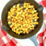 Oven Roasted Potatoes O'Brien cooking in a cast iron skillet.