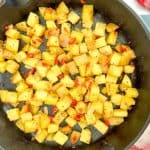 Oven Roasted Potatoes O'Brien with diced potatoes and red peppers in a skillet.
