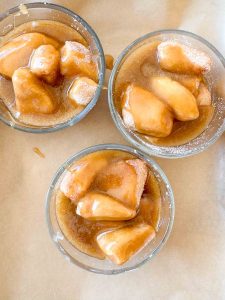 Three glass bowls filled with dough pieces coated in caramel sauce.