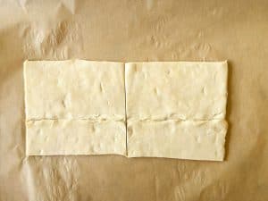 Two sheets of puff pastry cut into four rectangles on parchment paper before baking.